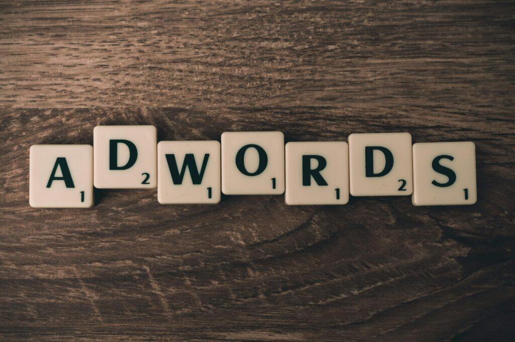 Scrabble tiles on a wooden surface spell out the word “ADWORDS.”. | Tsunami Reach