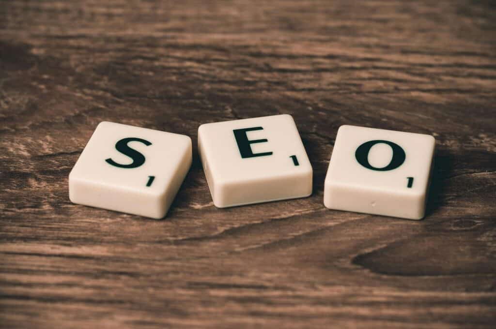 Three Scrabble tiles spelling "SEO" on a wooden surface. | Tsunami Reach