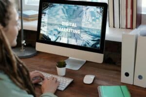 Person typing on a keyboard at a desk with a computer screen displaying "Digital Marketing". | Tsunami Reach