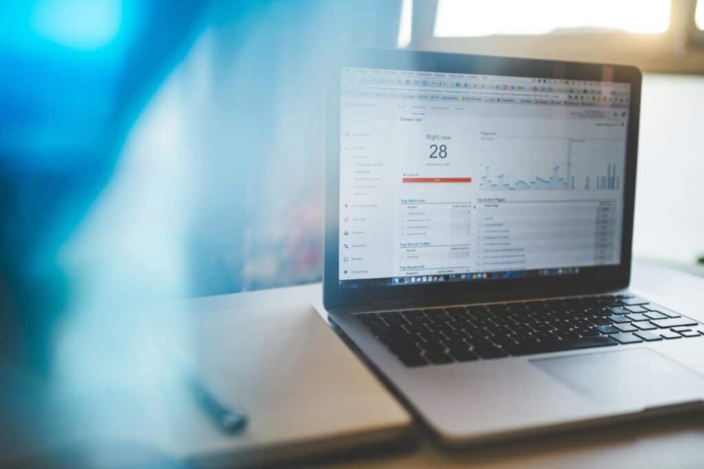 Laptop displaying website analytics next to a notebook and pen on a desk, with soft blue light in the foreground. | Tsunami Reach