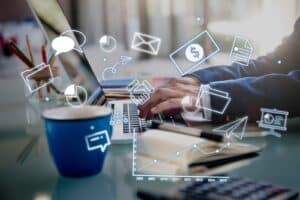 Person typing on a laptop with business and finance icons overlaid, including a chart, dollar, and communication symbols. | Tsunami Reach
