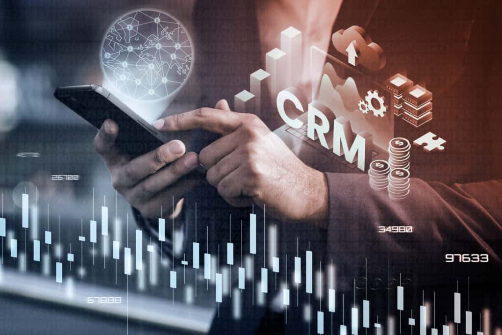 Businessperson using smartphone with CRM, financial charts, and digital interface graphics overlayed. | Tsunami Reach