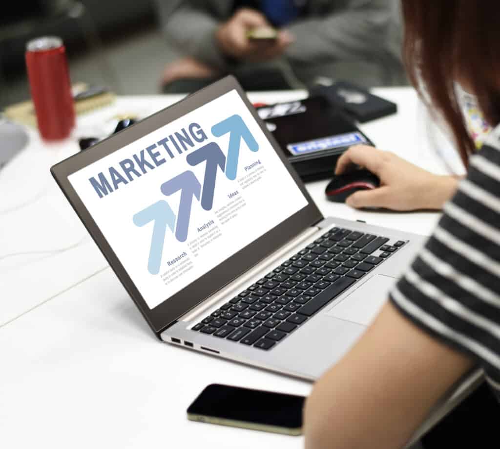 Person using a laptop displaying a marketing strategy with upward arrows and text in an office setting. | Tsunami Reach