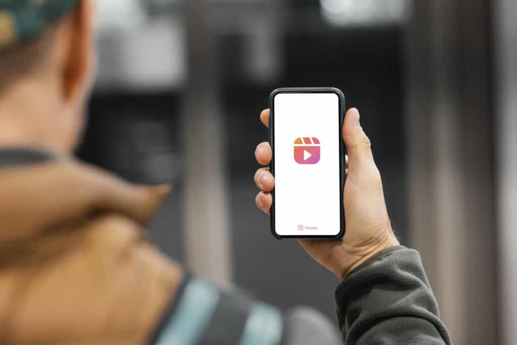 Person holding a smartphone displaying the Instagram Reels logo on the screen. | Tsunami Reach