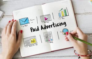 A person writes "Paid Advertising" in a notebook with sketches of email, video, ROI, website, and blog icons. | Tsunami Reach