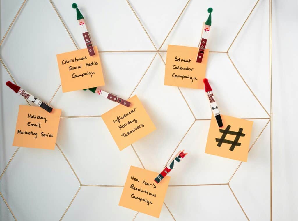 Five notes clipped to a wire grid, each listing a different holiday marketing campaign, with festive clothespins. | Tsunami Reach