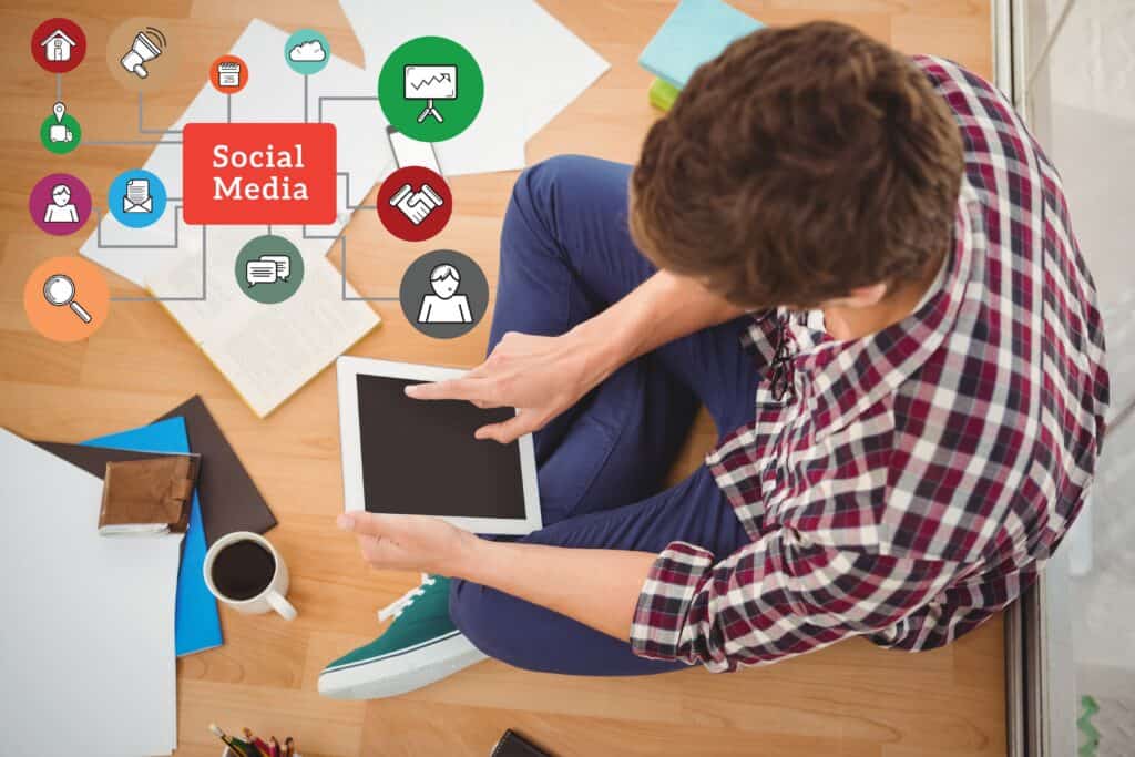 Man sitting on floor using tablet, with social media icons and documents spread around him. | Tsunami Reach