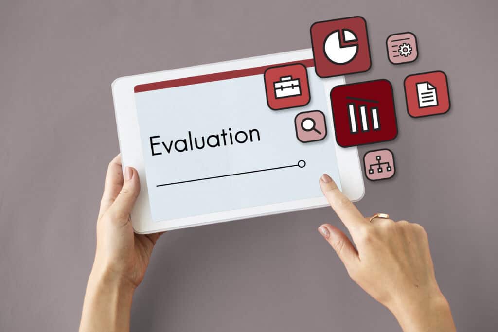 Person holding a tablet displaying "Evaluation" with business-related icons floating around the screen. | Tsunami Reach