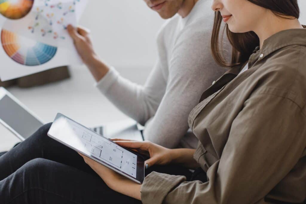 Two people sit together; one holds a tablet, the other holds a color chart with charts and graphs visible. | Tsunami Reach