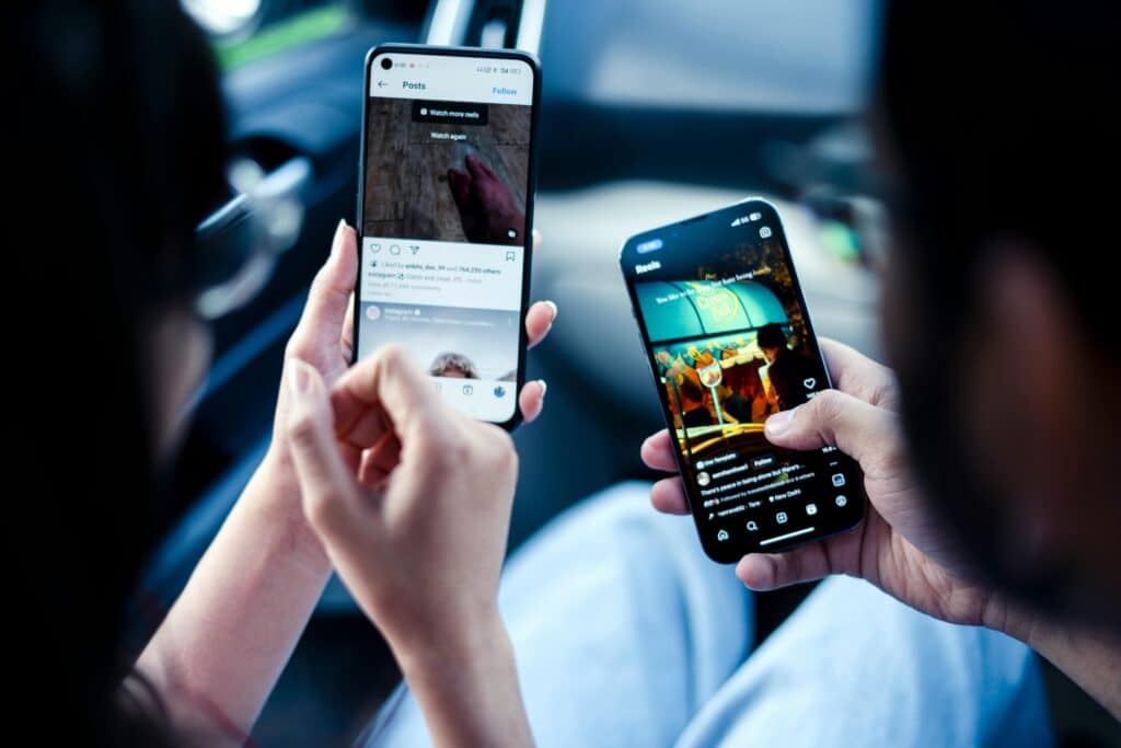 Two people sitting side by side, each using a smartphone and scrolling through social media feeds. | Tsunami Reach