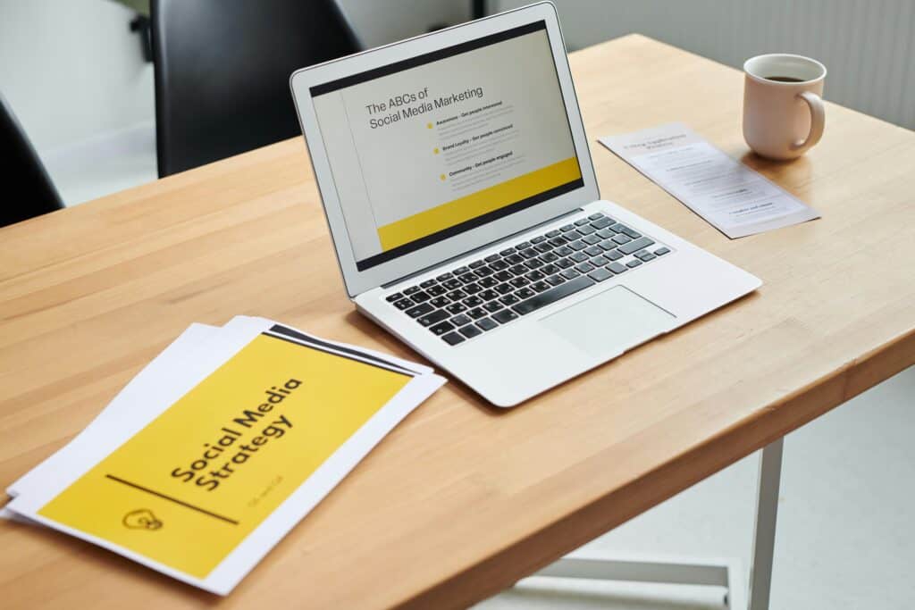 Open laptop on a desk displaying "The ABCs of Social Media Marketing," with documents and a coffee mug beside it. | Tsunami Reach