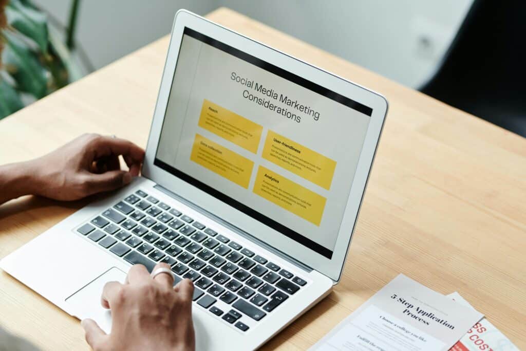 Person using a laptop displaying a slide titled “Social Media Marketing Considerations” with yellow text boxes. | Tsunami Reach