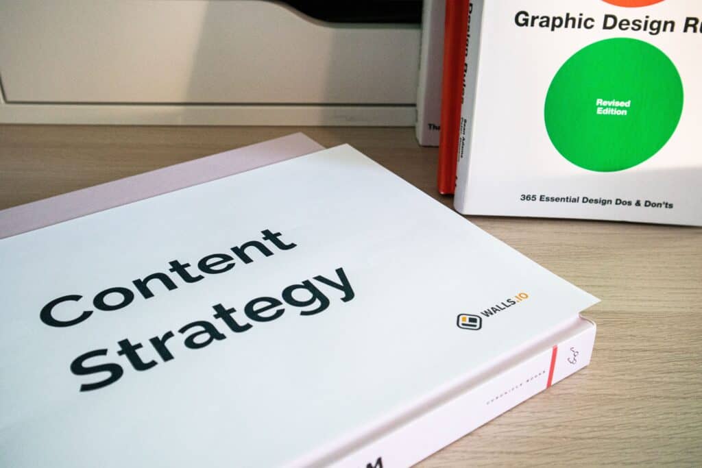 A book titled "Content Strategy" lies on a desk next to a "Graphic Design" and "Digital Marketing" book. | Tsunami Reach