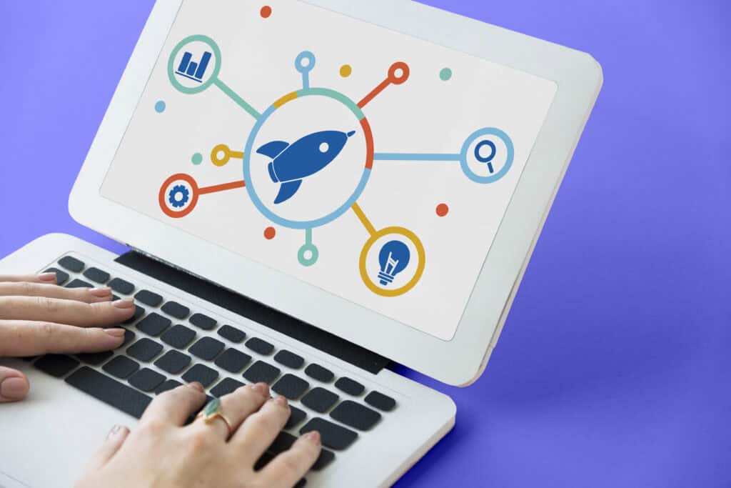 Hands typing on a laptop with a screen showing a rocket and connected icons, symbolizing startup or growth. | Tsunami Reach