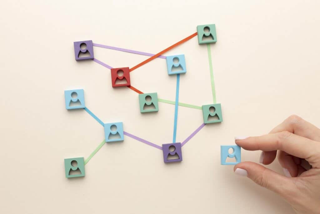Hand holding a blue avatar icon near a network of connected avatar icons on a light background. | Tsunami Reach