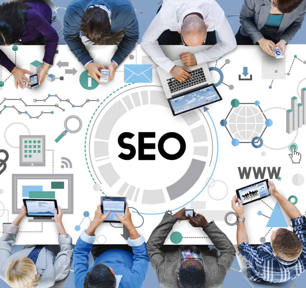 People using digital devices around a table with "SEO" and web-related graphics, symbolizing an SEO agency Singapore. | Tsunami Reach