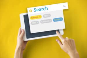 Person using a tablet with a search interface overlay showing tags: Content, SEO, SEM, Concept, and Words. | Tsunami Reach