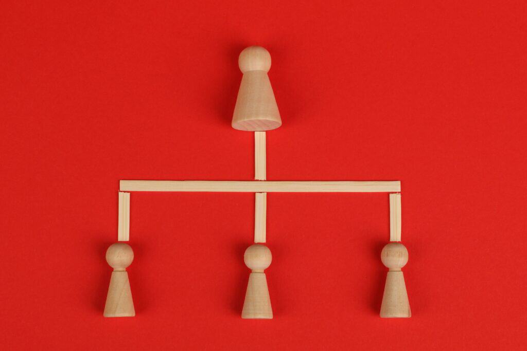 Wooden game pieces arranged in a hierarchy structure on a red background. | Tsunami Reach