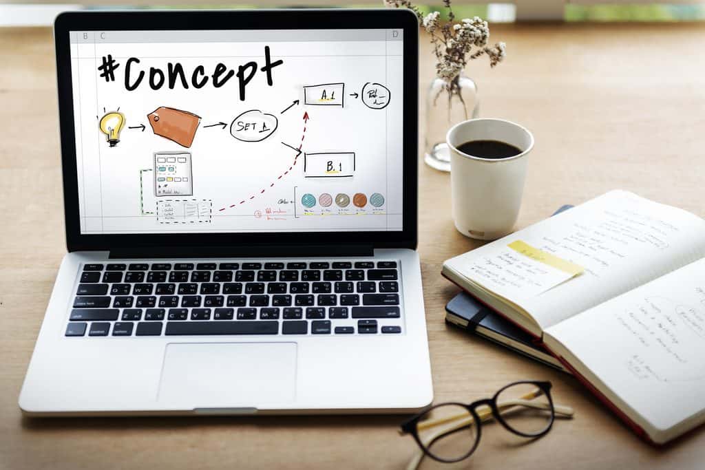 Laptop on desk displaying a flowchart titled “#Concept,” with coffee, notebook, and pen beside it. | Tsunami Reach
