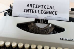 A typewriter types a sheet of paper with the words “ARTIFICIAL INTELLIGENCE” in bold, uppercase letters. | Tsunami Reach
