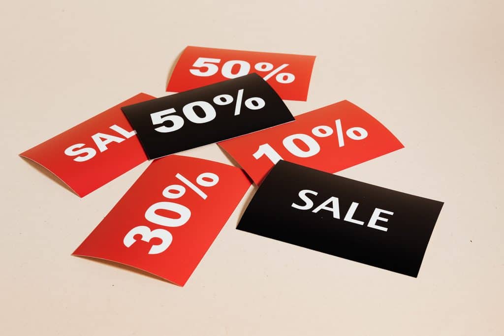 Red and black sale cards display discounts of 10%, 30%, 50%, and the word “SALE” on a light surface. | Tsunami Reach